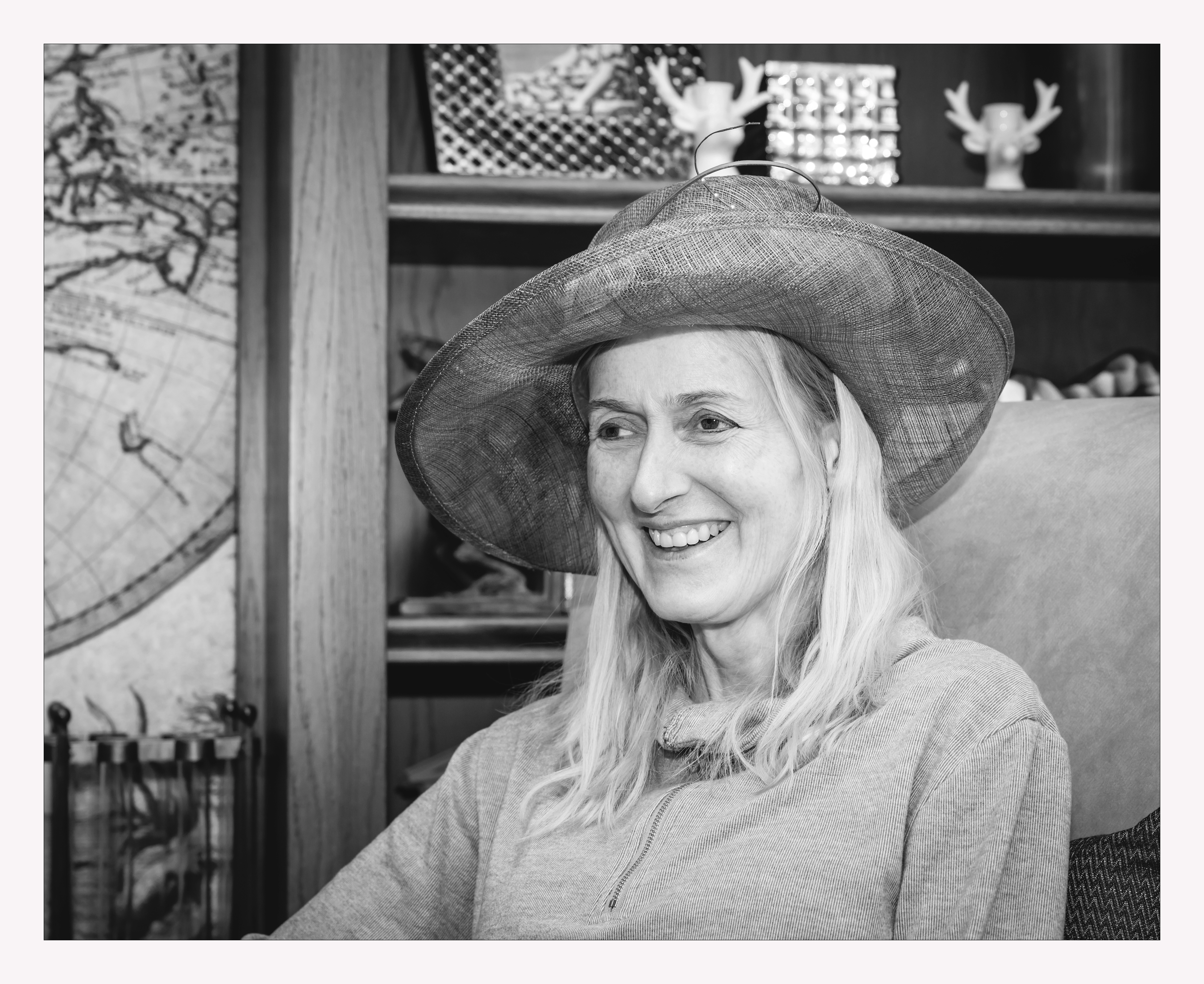 Black & White image of lady wearing a hat sitting in chair laughing